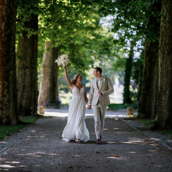 Schlosspark Eichtersheim, Angelbachtal Brautpaar läuft Hand in Hand durch die Allee im Schlosspark Eichtersheim, die Braut hebt den Strauß – Schlosspark Eichtersheim, Angelbachtal
