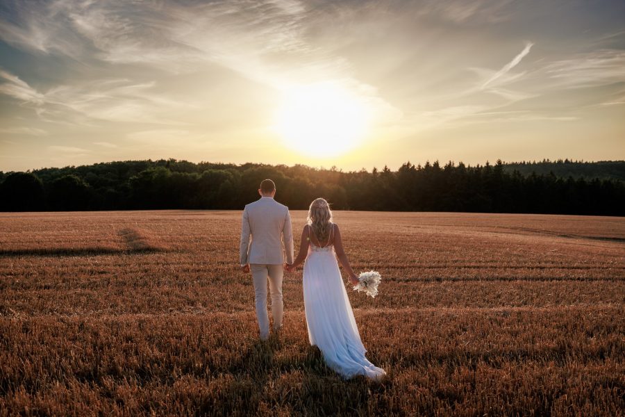 Felder bei Östringen Brautpaar geht Hand in Hand über ein Feld bei Östringen in den Sonnenuntergang – Felder bei Östringen