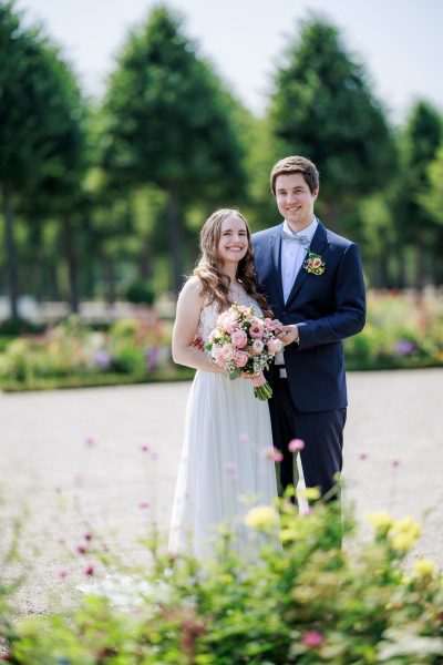 Schlossgarten Schwetzingen Brautpaar steht hinter Blumen im Schlossgarten Schwetzingen – Schlossgarten Schwetzingen
