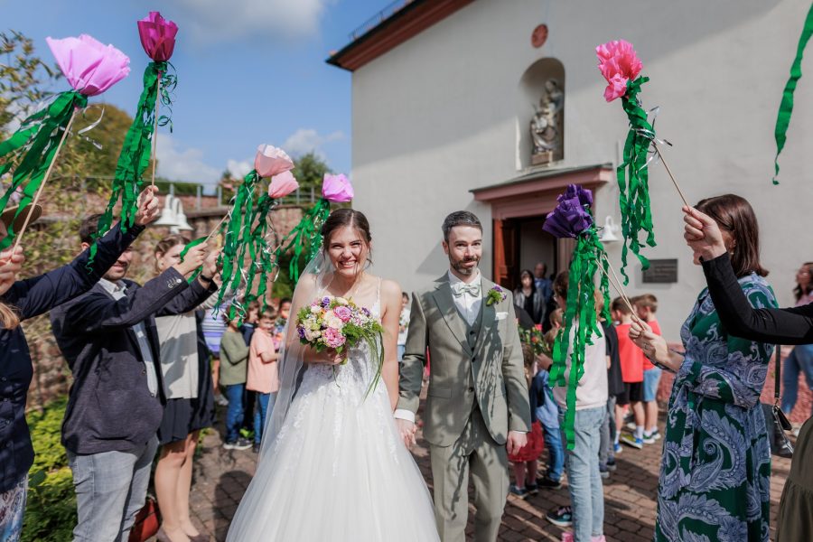 Die Gäste stehen mit grünen Girlanden Spalier vor der Kirche
