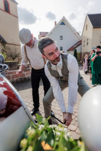 Der Bräutigam bindet Blechdosen an den Oldtimer