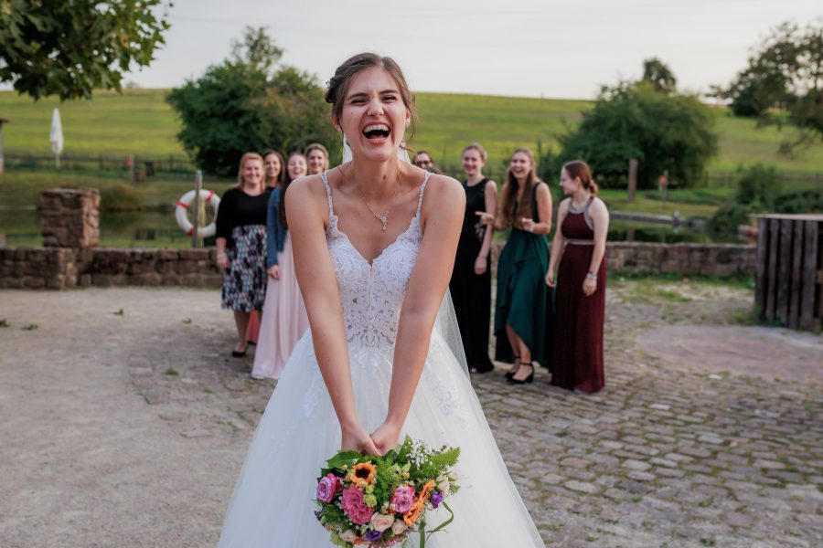 Landgut Lingental, Leimen Die Braut lacht mit dem Brautstrauß vor dem Werfen, die Freundinnen warten – Landgut Lingental, Leimen